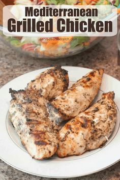 grilled chicken on a white plate next to a bowl of salad with the words mediterranean grilled chicken