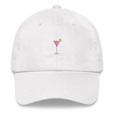 "Embroidered Cosmopolitan (Cosmo) Cocktail Dad Hats aren't just for dads. This one's got a low profile with an adjustable strap and curved visor. Available in black, navy, light blue, pink and white.  * 100% chino cotton twill * Unstructured, 6-panel, low-profile * 6 embroidered eyelets * 3 ⅛\" (7.6 cm) crown * Adjustable strap with antique buckle * Blank product sourced from Vietnam or Bangladesh This product is made especially for you as soon as you place an order, which is why it takes us a bit longer to deliver it to you. Making products on demand instead of in bulk helps reduce overproduction and reduces waste, so thank you for making thoughtful purchasing decisions!" Cosmo Cocktail, Cocktail Hat, Cosmopolitan, Trucker Cap, Pink And White, Dad Hats, Low Profile, Cotton Twill, Cosmos