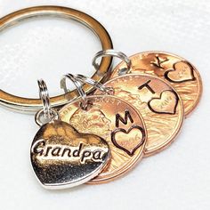 three coins with the word grandpa written on them are sitting in front of a keychain