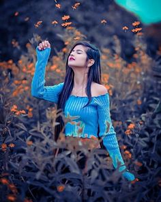 a woman with long hair standing in a field full of yellow flowers and flying butterflies