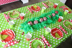 a green table topped with lots of red and white plates covered in candy canes