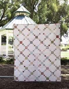 a white quilt hanging from the side of a wooden pole in front of a gazebo