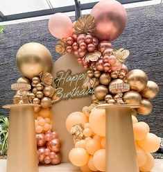 a birthday cake made out of balloons and golds on display in a building with a sign that says happy birthday