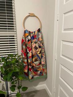 a colorful skirt hanging on the wall next to a potted plant