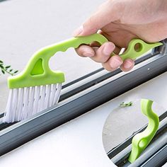 a hand holding a green brush on top of a window sill