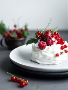 a white plate topped with a cake covered in whipped cream and berries