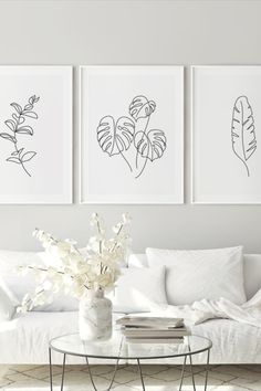 three black and white prints hang on the wall above a coffee table in a living room