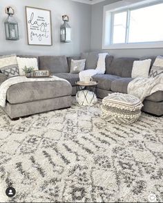 a living room with gray couches and white rugs on the floor in front of a large window