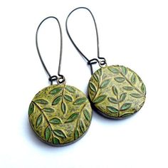 pair of earrings with green leaves painted on the front and back of each earring