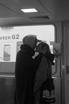 two people standing next to each other in front of a subway train car with the doors open