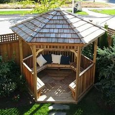 a wooden gazebo sitting on top of a lush green field