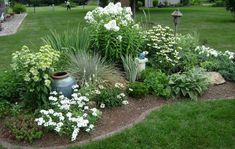 a garden filled with lots of different types of flowers and plants in front of a house