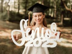 a girl in graduation cap and gown holding up a cutout that reads'senior 2013 '