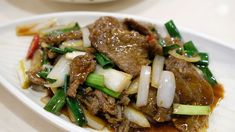 a white plate topped with meat and veggies covered in gravy on top of a table