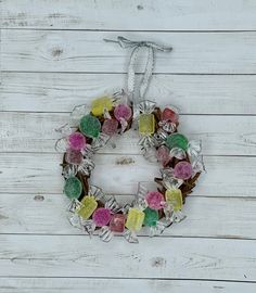 a wreath made out of gummy bears hanging on a white wooden wall next to a pair of scissors