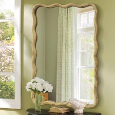 a mirror sitting on top of a dresser next to a window