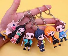 a hand holding several key chains with cartoon characters on them