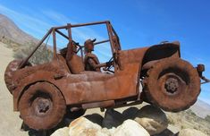 an old rusted out car sitting on top of some rocks