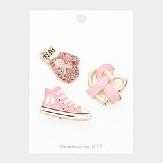 three pins with pink and white designs on them, one in the shape of a shoe