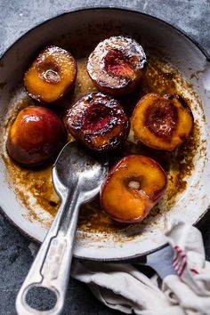 a pan filled with cooked peaches on top of a table next to a spoon