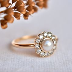 a close up of a ring on a table with flowers in the background and a white cloth