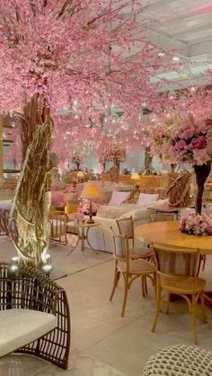 a room filled with lots of tables and chairs covered in pink cherry blossom tree branches