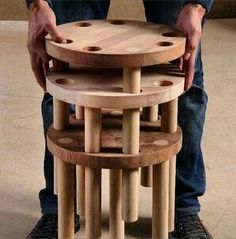 a man standing next to a stack of wooden stools on top of each other