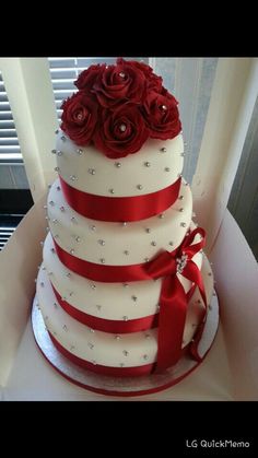 a three tiered wedding cake with red roses on top