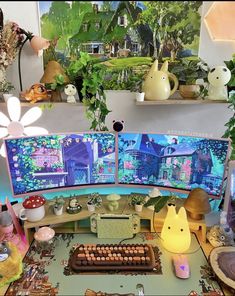 a desk with two computer monitors on top of it and plants in the back ground