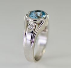 A lovely oval aquamarine from Brazil with two flush set diamonds in this 14k white gold ring. Metal: 14K white gold The aquamarine is from Brazil and weighs 2 carats and measures 9 x 7mm oval AA color The two round brilliant cut Diamonds have a total weight of .18 carats G-H color VS2 clarity The ring is 10.4mm wide tapering to 3.4mm and the height is 6.5mm Size: 6 1/2-6 3/4 Aquamarine, the March birthstone, is a member of the beryl family, which also includes emerald, morganite and yellow beryl Oval Aquamarine Anniversary Birthstone Ring, Oval Aquamarine Birthstone Ring For Anniversary, Oval Topaz Ring With Diamond Accents For Anniversary, Oval Blue Topaz Birthstone Ring For Anniversary, Oval Topaz Ring With Bezel Setting For Anniversary, Oval Platinum Topaz Ring For Anniversary, Modern Oval Birthstone Ring For Anniversary, Stowe Vt, Flush Set Diamond