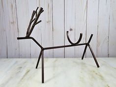 a metal deer sculpture sitting on top of a white marble counter next to a wooden wall