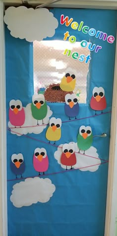 a door decorated with birds and clouds for a welcome to our nest sign on the front