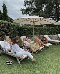 a group of women sitting on lawn chairs under an umbrella