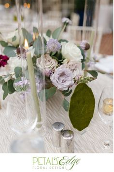 there is a table with flowers and candles in the center, along with wine glasses