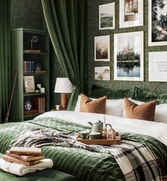 a bed with green walls and pictures on the wall above it, next to a lamp