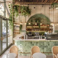 the interior of a restaurant with green tiles and plants hanging from the ceiling, along with tables and chairs