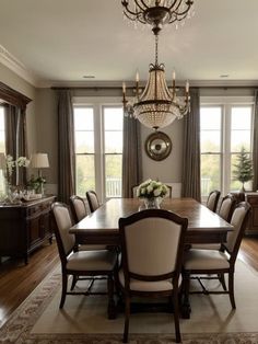 a formal dining room with chandelier and large table in front of two windows