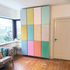 a living room filled with furniture next to a window and a wooden floor covered in multicolored tiles