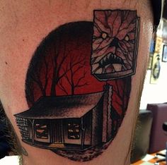 a man's leg with a tattoo on it that has a house in the background