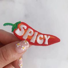 a person holding up a small patch with the word spicy on it's side