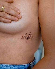 a woman's breast with an all seeing tattoo on her left side, and the sun in the middle