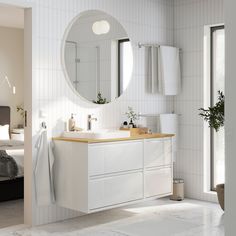 a white bathroom with a large round mirror