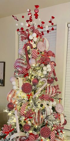 a christmas tree decorated with red and white ribbons, bows, and candy canes