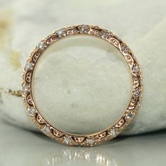 an image of a wedding ring with diamonds on the inside and in the outside, sitting on top of a rock