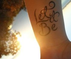 a woman's wrist with the words let it be written in cursive writing