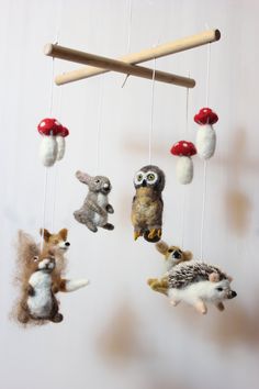 an animal mobile is hanging from a wooden rod with mushrooms and other stuffed animals on it