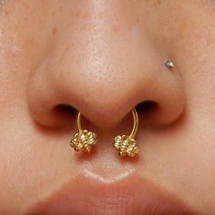 a close up view of a nose with two small gold flowers on it's side