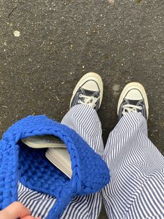 someone is holding a cell phone in their hand while wearing blue and white striped pants