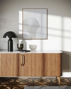 a modern sideboard with an art print on the wall above it and a lamp next to it