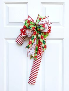 a red and green christmas bow hanging on a white door with polka dots, candy canes, and snowflakes